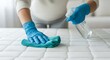 © Rasel - Person in blue gloves cleaning a mattress with a spray bottle and cloth