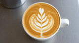Overhead shot of a latte art with a heart and leaf design in a white cup