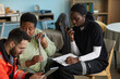 © DragonImages - Middle aged Black woman holding cane sitting next to young female nurse using walkie talkie and clipboard with male paramedic showing information on tablet, discussing emergency hospitalization plan