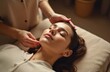 © Pete - Young woman receives face and head massage from therapist hands. She rests peacefully with eyes closed, enjoying gentle touch and relaxation in a quiet studio setting. This therapy promotes wellness.