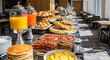 © Gabriel - Ultra-realistic American hotel breakfast buffet with pancakes, scrambled eggs, bacon, sausages, pastries, fruits, and orange juice dispensers, modern dining hall filled with natural sunlight and warm