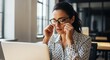 © Running opossum - focused woman adjusting glasses working on laptop in modern office with natural light