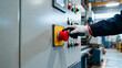 © Evgenia - Gloved worker hand pressing red emergency stop button on industrial control panel