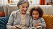 © Douglas - Happy grandmother and granddaughter reading a book together on the sofa at home