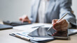 © Garun Studios - Businessperson using a digital tablet and stylus with financial reports, representing data analysis, audit review, and strategic project management in modern office work.