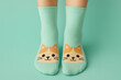 © Chanita - Cute cat face socks on feet against pastel turquoise background. cozy and playful fashion concept for fun home lifestyle, showing colorful textile design and pattern