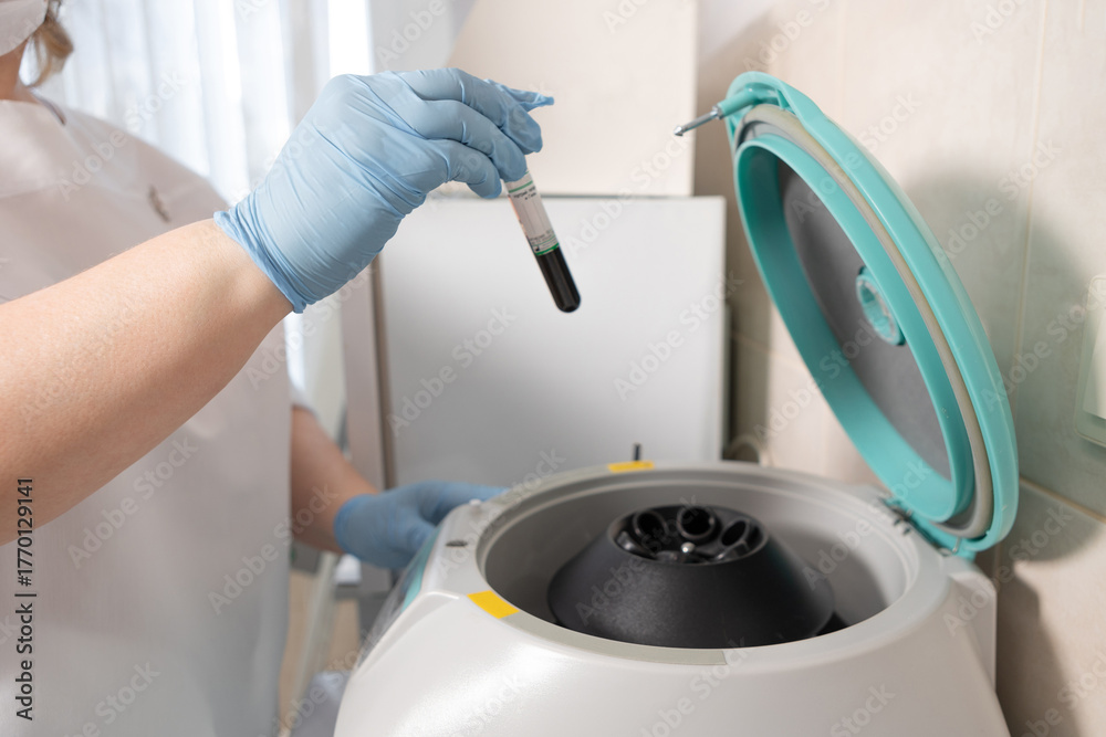 The nurse puts a tube of the patient's blood into the centrifuge ...