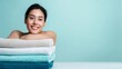 © Salander Studio - smiling young woman leaning her head on a stack of fresh towels