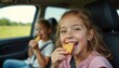 © Viktor - Two happy girls eat crackers in car during road trip. Children enjoy snack while traveling on vacation. Passengers smile and have fun on journey together.