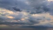 © Sarmiko - Dramatic cloudy sky with soft golden light breaking through thick gray clouds before a rainstorm, perfect for themes of climate, tranquility, or changing weather