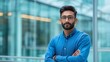 © Yuliia Malovana - Portrait of professional young Indian businessman with glasses and beard standing with arms crossed confidently in office environment, copy space.