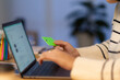 © Studio Marmellata - Crop anonymous young woman using green plastic card for online shopping on internet website at home