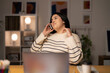 © Studio Marmellata - Young Arab female remote employee in casual clothes speaking via smartphone with client while working on project remotely using laptop