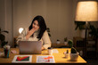 © Studio Marmellata - Positive young Arab woman in casual sweater sitting at table with laptop and making a video call on project during evening time