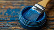 © sommersby - Vivid blue paint in small container with brush dipped inside, sitting on weathered wooden table splattered with matching blue hues, symbolizing art and renovation