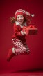 © Khawla - Happy Little Christmas Elf Jumping with Gift on Red Background