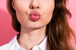 © deagreez - Close-up of a young woman puckering lips for a playful expression against a pink background showcasing beauty and style