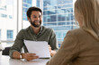 © fizkes - Cheerful young employer man holding paper resume, talking to candidate