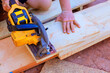 © ungvar - Worker utilizes power saw to cut plank of wood during DIY project