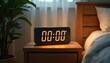 © miss irine - Digital clock displays zero time on bedside table at night. Time symbolizes beginning of new day new era. Clock is on nightstand near bed in room.