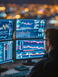 © Daria - Focused young analyst working late at night monitoring multiple financial data charts and stock market trends displayed on several computer screens