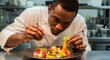 © Nique - Portrait of an African chef plating a dish with artistic presentation