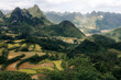 © Connect Images - Rolling green hills with terraced fields against a backdrop of jagged mountain peaks. NguyÍn BÏnh District, Cao Bang, Vietnam