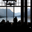 © Connect Images - Silhouetted people enjoy a stunning mountain lake view through large windows. Waterton Park, Alberta, Canada