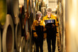 © Montri - Industrial workers inspecting large metal coils in warehouse aisle. Wearing safety uniforms and helmets. material stock check, factory inventory, manufacturing. engineer, two worker. logistics.