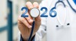 © kilimni - Doctor's hand with medical stethoscope with numbers 2026, white and blue hospital setting. New Year's banner in medicine. Clinics and hospitals, GP practice, beginning and plan for new season