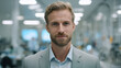 © britaseifert - Portrait of a blonde man in his early-30s wearing a light-gray suit, standing in a high-tech lab with subtle clinical trial imagery in the background