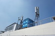 © Abu Tami - antennas and signal transmitting devices on the roof of a white building with a blue water tank next to it, the clear sky in the background emphasizes the elements of modern technology