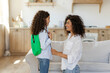 © Home-stock - Mother with child girl getting ready for school in the morning, mom helping daughter wearing school bag and talking, side view