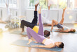 © JackF - In sports club during multinational Pilates training, girl leads class, lying on mat performs variety of exercises to strengthen muscles of press, buttock bridge with lifting outstretched leg.