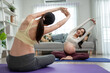 © Kawee - Asian two pregnant women doing yoga workout in living room at home.