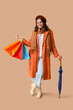 © Pixel-Shot - Young woman with shopping bags and umbrella on brown background