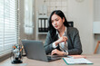 © Crystal - Young Asian businesswoman seriously thinking while working on laptop at desk in a modern home office