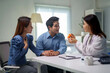 © Crystal - Doctor in white coat explaining medication and healthcare advice to an Asian couple during a medical consultation in a clinic