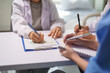 © Crystal - Medical team collaborating, preparing documents and writing notes during a healthcare meeting, focusing on patient care and data recording