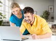 © BillionPhotos.com - Happy young couple with laptop relaxing at home.