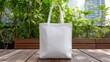 © Stock by Hemal - A High Resolution image of white canvas tote bag on a wooden table with greenery background.