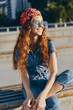 © SHOTPRIME STUDIO - lifestyle woman in modern boho-western denim street style with red bandana and sunglasses, smiling outdoors in warm film color sunlight, casual urban vibe