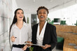 © fizkes - Laughing two young women coworkers having fun tracking tasks progress