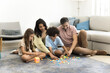 © fizkes - Family building blocks together on carpet in living room
