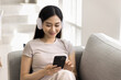 © fizkes - Woman in headphones enjoying digital content on smartphone