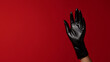 © photo for everything - A hand clad in a sleek, dark glove reaches out against a bold red backdrop, creating a stark contrast. The glossy texture adds a touch of modern intrigue.