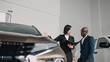 © wedmoments.stock - African American man engaging with a female car salesperson in a dealership, discussing vehicle features and options, showcasing the car buying experience and customer service