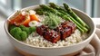 © fayanashakira - Overhead view of a vibrant healthy meal in a ceramic bowl featuring glazed tofu broccoli florets asparagus spears and quinoa with fresh garnishes in natural lighting