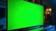 © Peindre - 暗いリビングルームに置かれた薄型テレビの画面が緑色の背景（クロマキー）で表示されているクローズアップ。 | Close-up of a slim television screen displaying a green background (chroma key) in a dark living room setting.