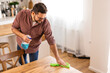 © Graphicroyalty - A man is cleaning a table at home, wiping down the surface to maintain a clean and organized space. The image captures a moment of home upkeep and attention to cleanliness in a cozy, everyday setting.